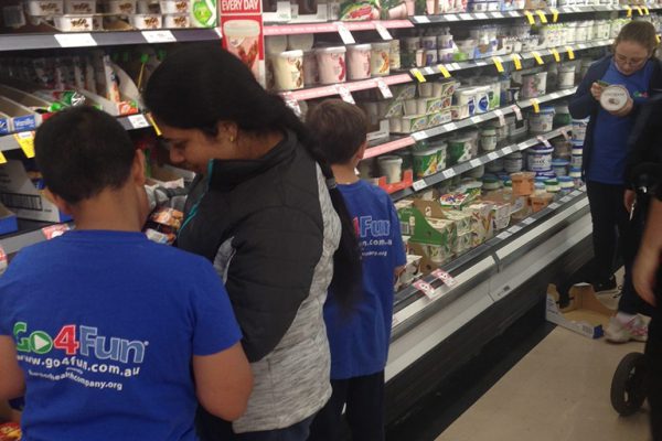 Parents and children reading nutrition labels at the supermarket. Link displays a larger version of the image.